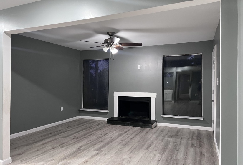 Unfurnished living room featuring a fireplace with raised hearth, ceiling fan, and light wood-style flooring