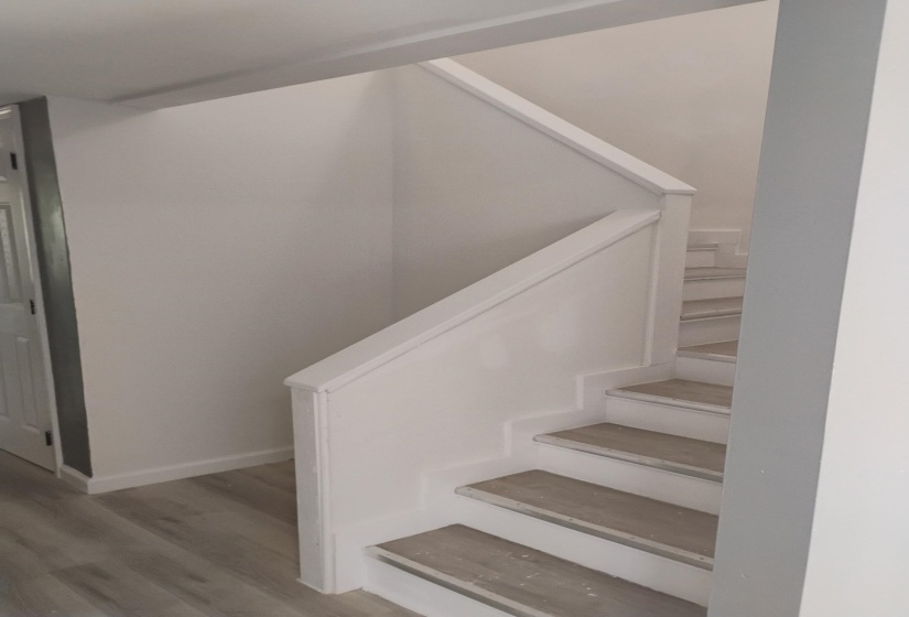 Staircase with wood finished floors and baseboards