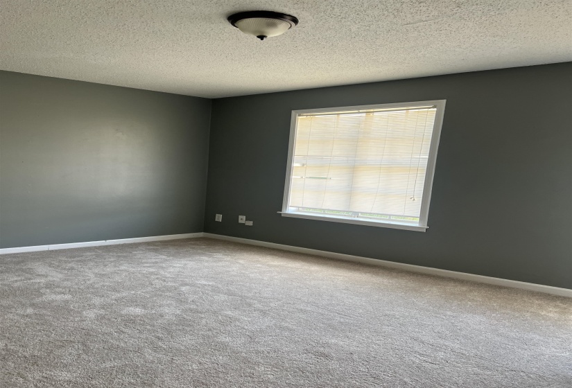 Carpeted spare room featuring a textured ceiling and baseboards