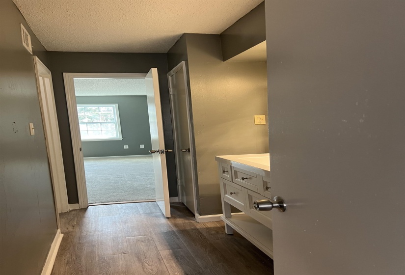Bathroom with a textured ceiling, vanity, and dark wood-style flooring