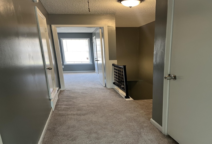 Corridor with a textured ceiling and light colored carpet