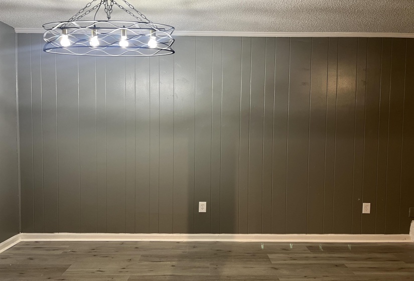 Unfurnished dining area featuring wood finished floors, crown molding, wooden walls, and a textured ceiling