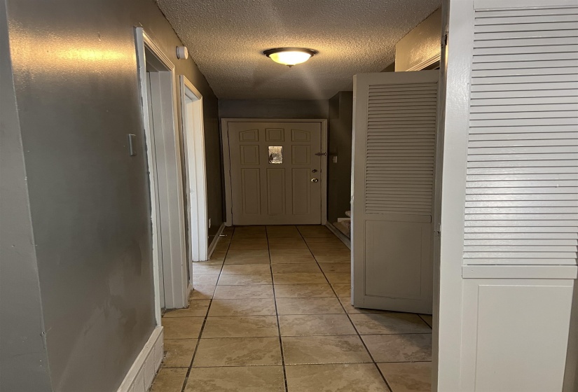 Hallway featuring a textured ceiling and light tile patterned flooring