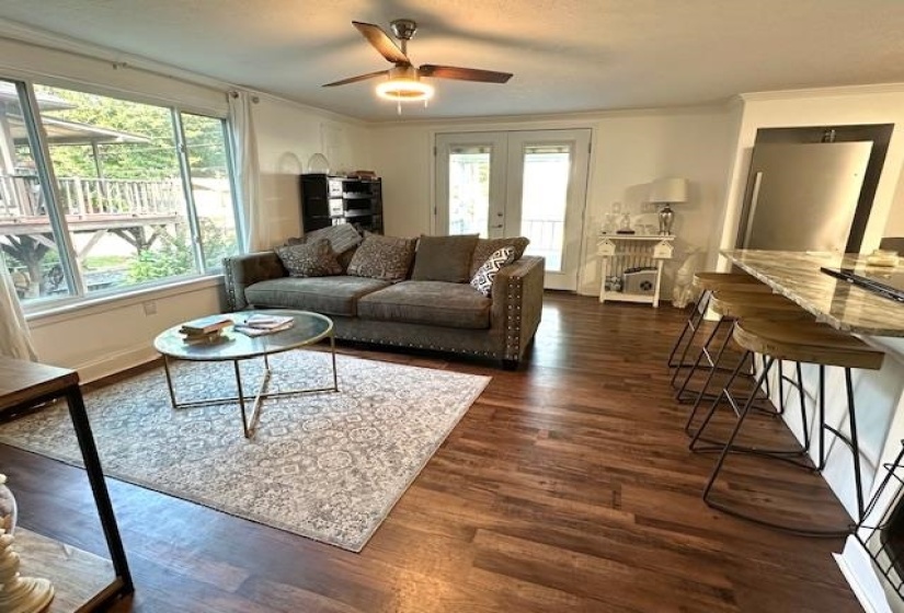 Living room with dark hardwood / wood-style flooring, ceiling fan, ornamental molding, and a wealth of natural light