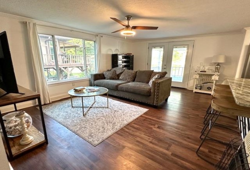 Living room with dark hardwood / wood-style flooring, a textured ceiling, a wealth of natural light, and ceiling fan