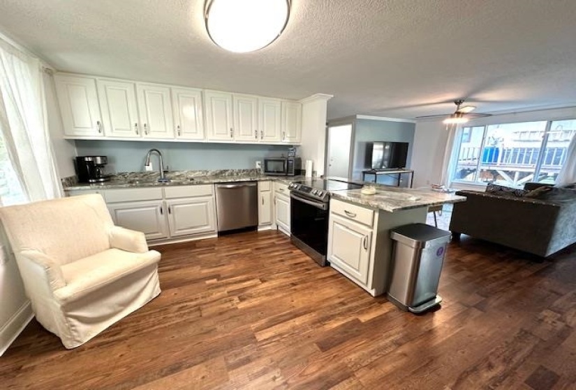 Kitchen featuring appliances with stainless steel finishes, light stone countertops, dark wood-type flooring, white cabinets, and ceiling fan