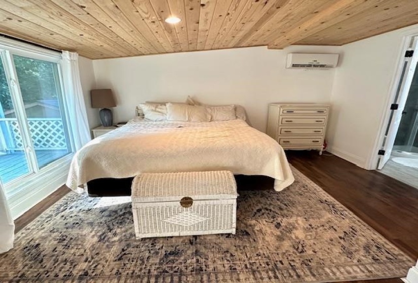 Bedroom with hardwood / wood-style flooring, wood ceiling, an AC wall unit, and access to exterior