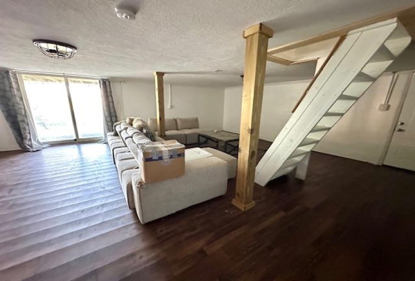Den with hardwood / wood-style floors, a textured ceiling, and ornate columns