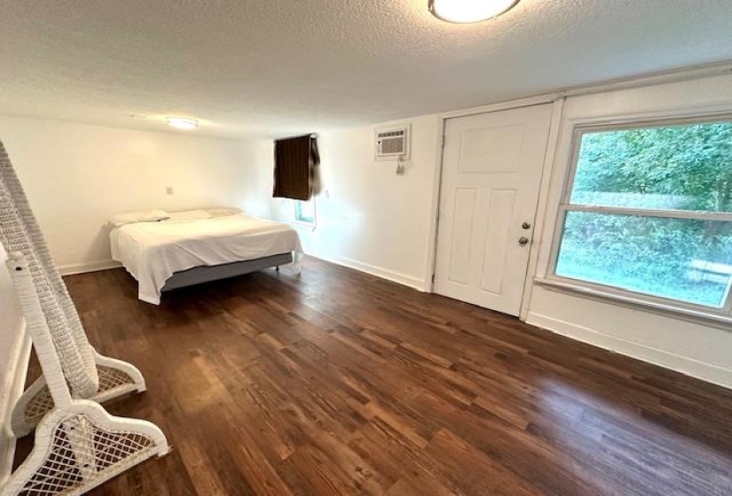 Bedroom featuring a textured ceiling, dark wood-type flooring, and an AC wall unit