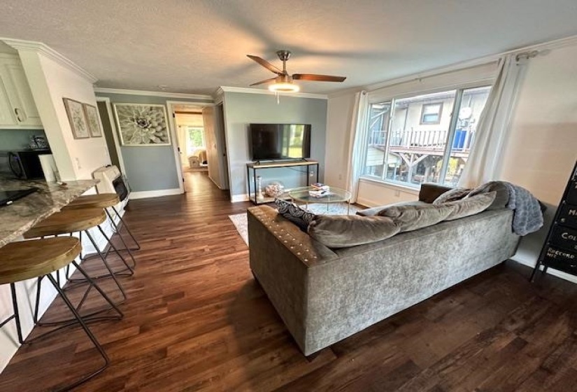 Living room featuring a textured ceiling, ceiling fan, dark hardwood / wood-style flooring, and crown molding
