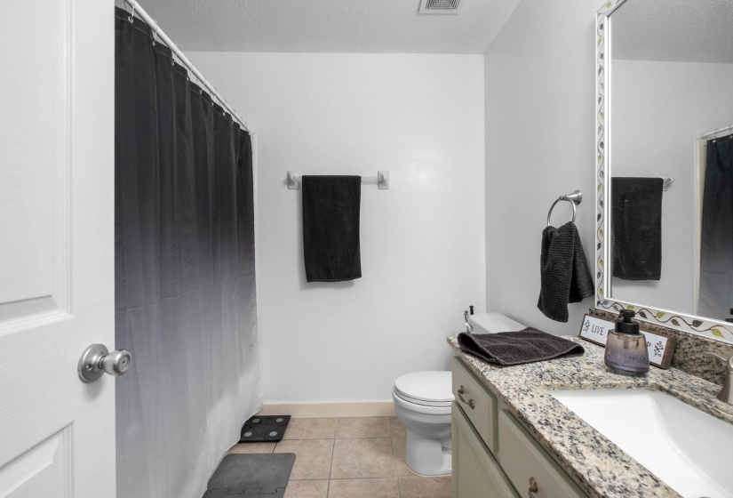 Bright and functional full bath featuring granite countertops, ample vanity storage, neutral finishes, and a tub/shower combination. Clean, well-maintained, and move-in ready, offering comfort and convenience for family members and guests alike.