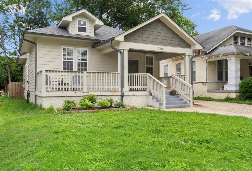 View of front facade featuring a front yard, roof with shingles, and a porch
