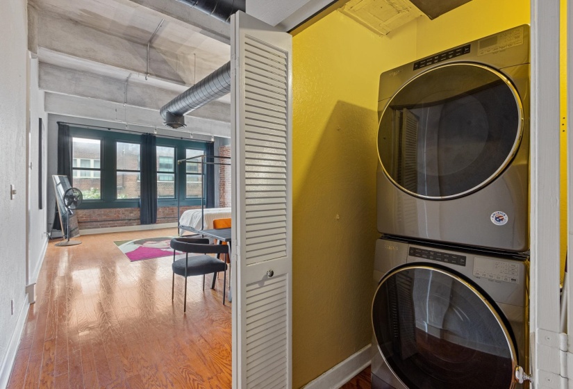 Laundry room featuring estacked washer and dryer and wood finished floors