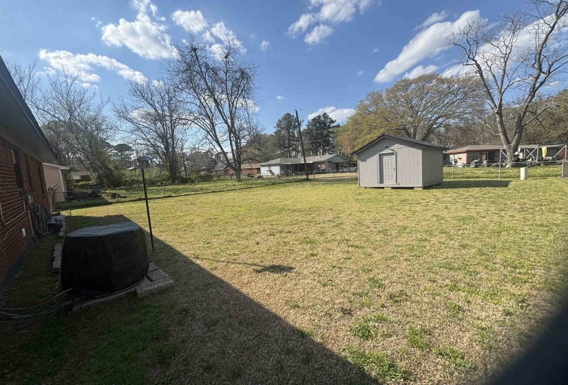 Fenced backyard featuring a storage unit