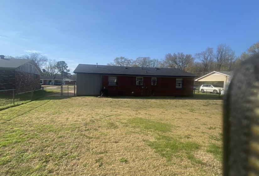 Rear view of property with a fenced backyard, a gate, and brick siding
