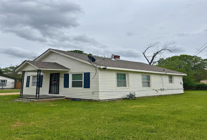 View of front of property featuring a porch, roof with shingles, a chimney, and a front lawn