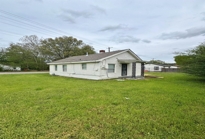 Rear view of property with a yard, roof with shingles, and a chimney