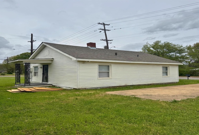 View of home's exterior with roof with shingles, a chimney, and a lawn