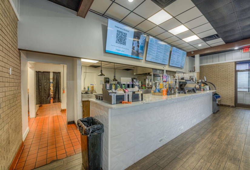 Kitchen featuring brick wall, a paneled ceiling, and light stone countertops
