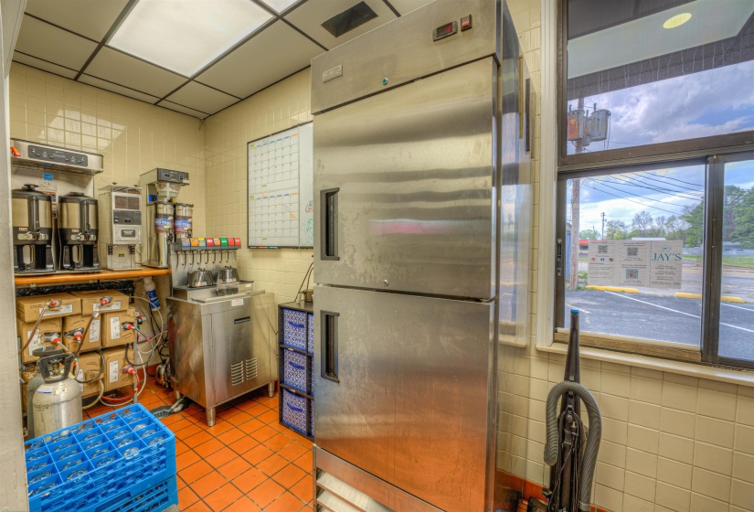 Kitchen with stainless steel refrigerator, a paneled ceiling, and tile walls
