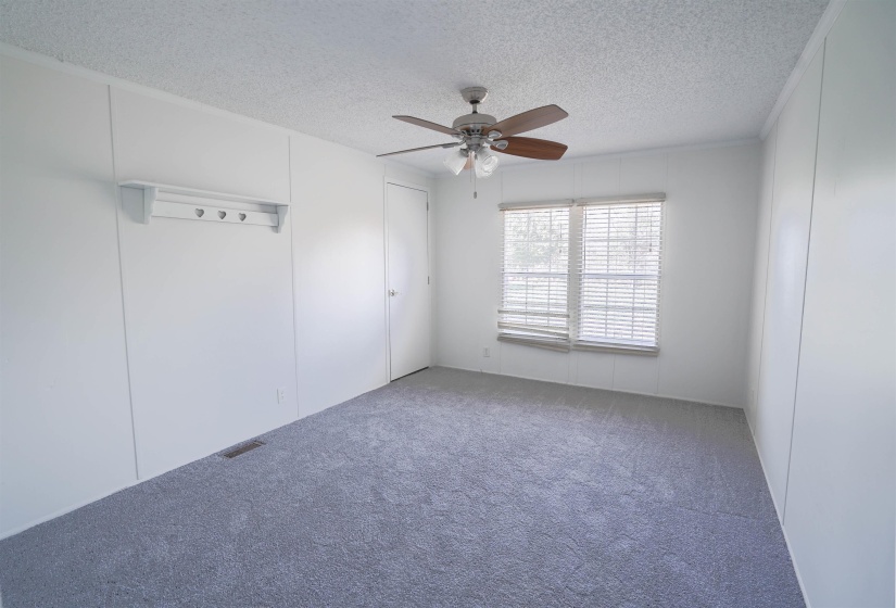 Empty room with a textured ceiling, a ceiling fan, carpet, and a decorative wall