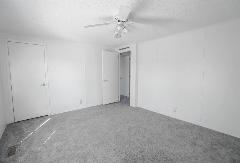 Unfurnished bedroom featuring a textured ceiling, carpet flooring, and a ceiling fan