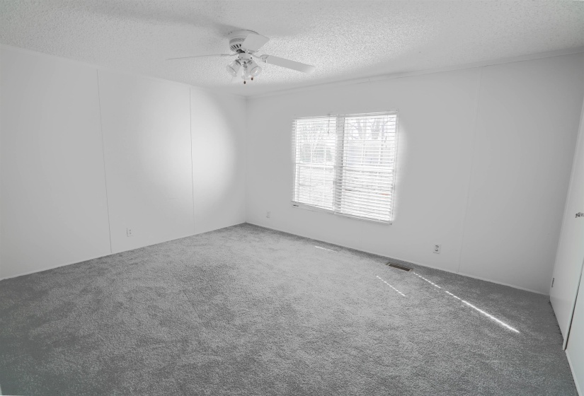 Carpeted empty room with a textured ceiling and ceiling fan