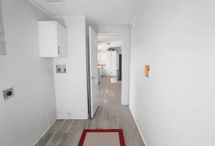 Laundry room with washer hookup, light wood finished floors, a textured ceiling, crown molding, and cabinet space