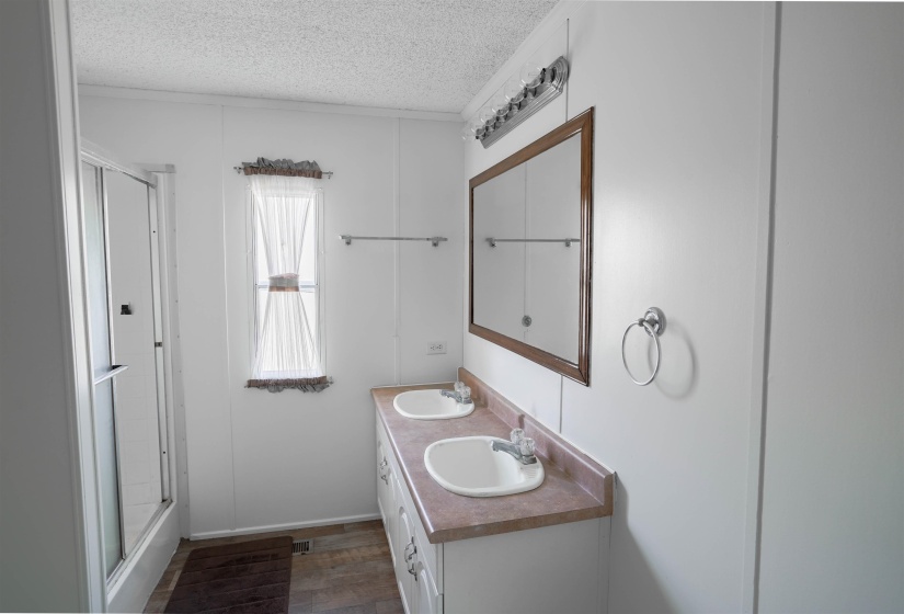 Bathroom with double vanity, a textured ceiling, and dark wood finished floors