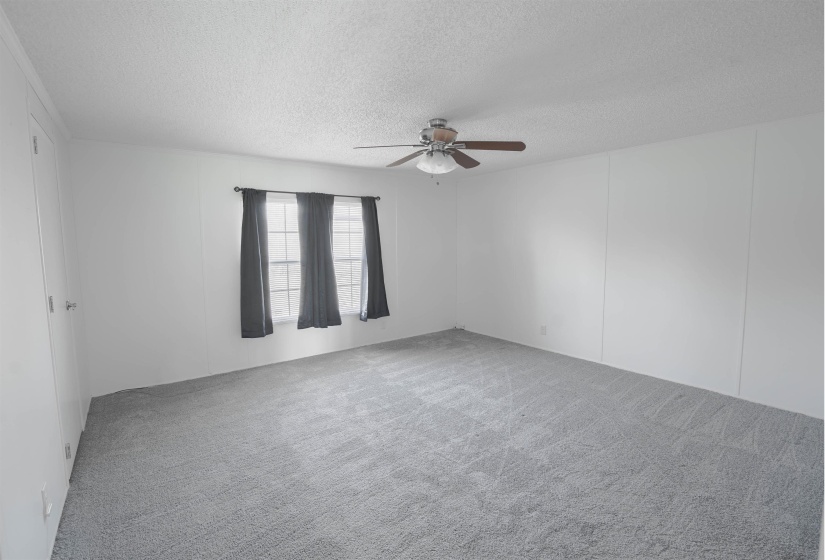 Carpeted spare room with a textured ceiling and a ceiling fan