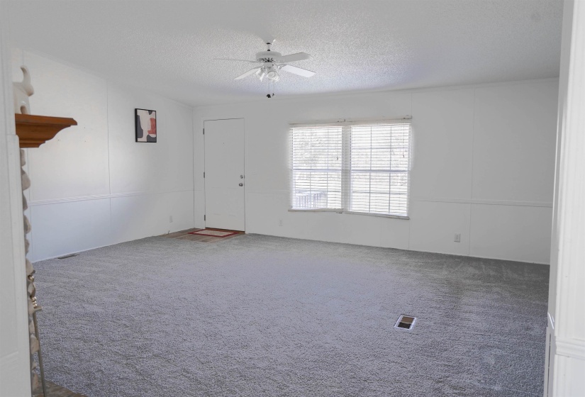 Carpeted empty room featuring a textured ceiling and a ceiling fan