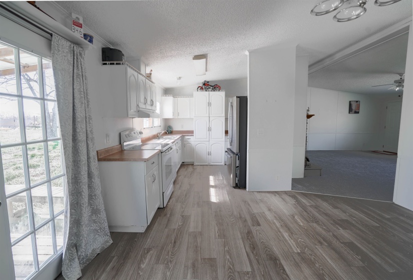 Kitchen featuring white cabinets, white range with electric cooktop, freestanding refrigerator, a textured ceiling, and light wood finished floors