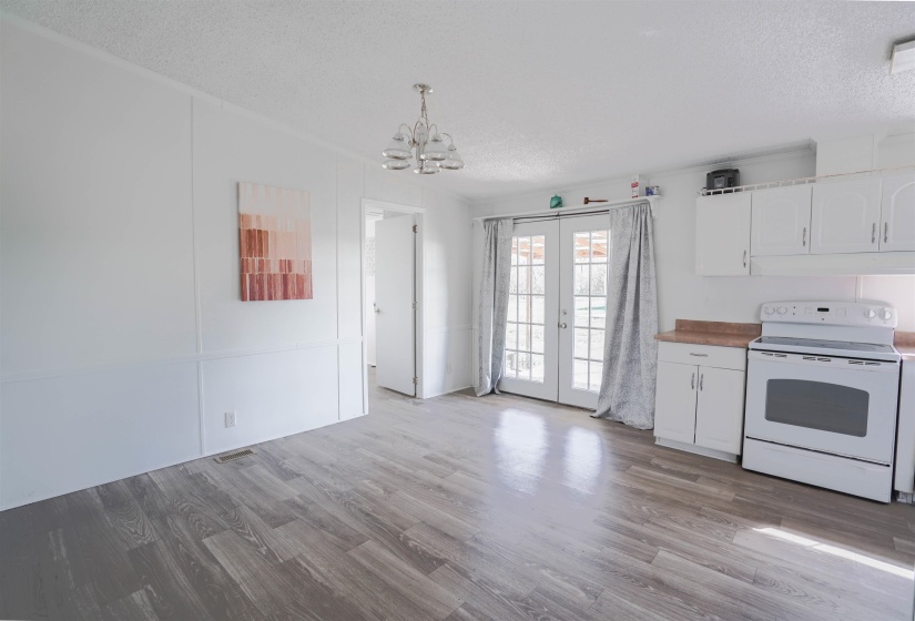 Kitchen featuring white cabinets, white electric range, a textured ceiling, french doors, and light wood finished floors