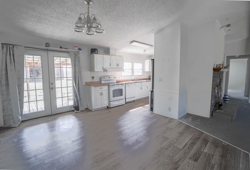 Kitchen with white appliances, a textured ceiling, white cabinets, dark wood-style floors, and suspended lighting