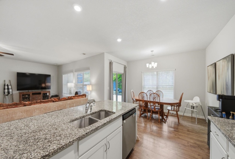 Kitchen featuring light stone counters, white cabinets, dishwasher, light wood-type flooring, and open floor plan