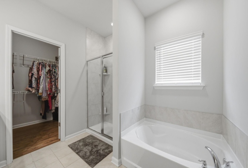 Full bathroom featuring light tile patterned floors, a shower stall, a spacious closet, and a bath
