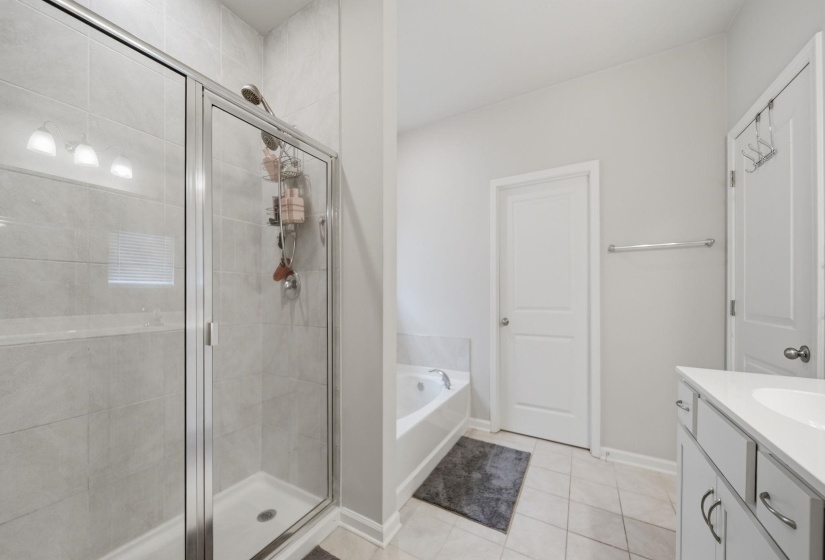 Bathroom featuring vanity, a bath, a shower stall, and light tile patterned floors