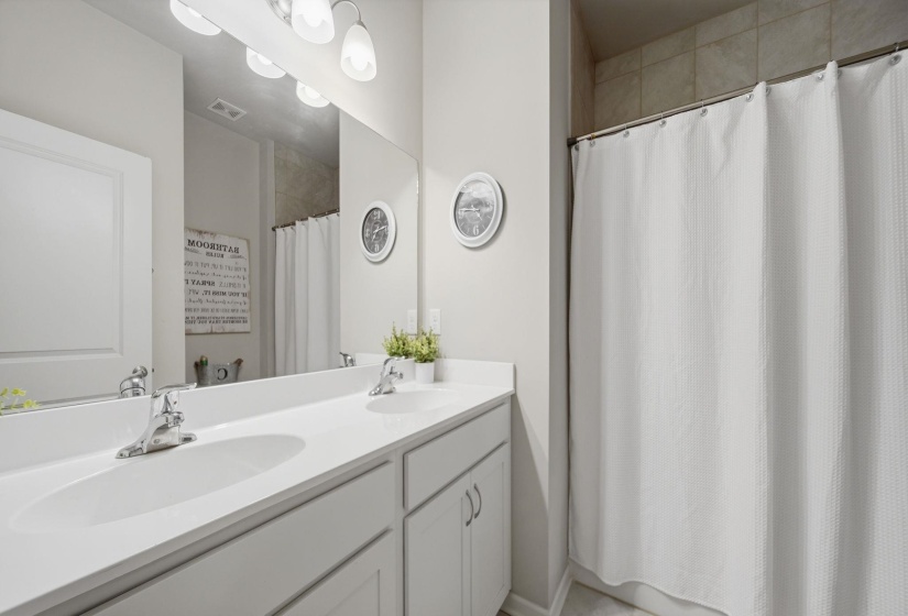 Full bath with double vanity and a shower with curtain