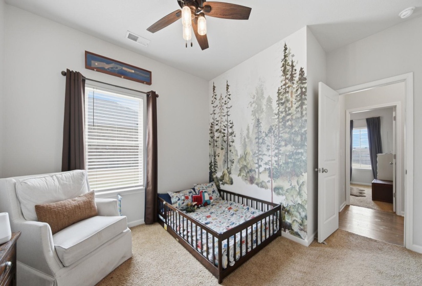 Bedroom with light carpet, a nursery area, and ceiling fan