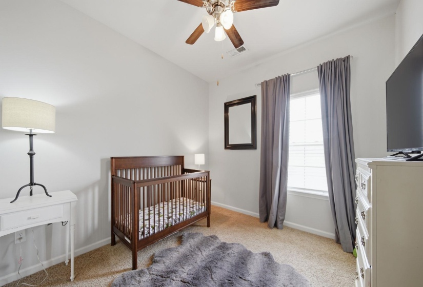 Bedroom featuring a nursery area, light colored carpet, ceiling fan, and vaulted ceiling