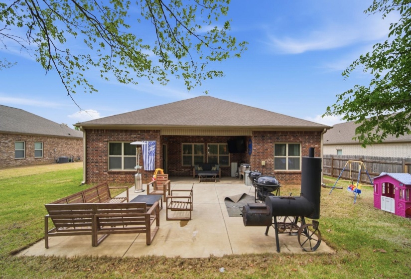 Rear view of house featuring an outdoor lounge area, a patio, a lawn, brick siding, and roof with shingles