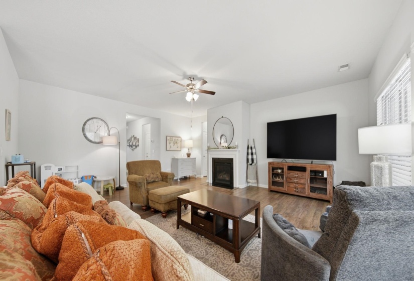 Living area featuring a glass covered fireplace, a ceiling fan, and wood finished floors