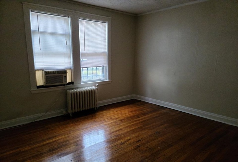 Unfurnished room featuring dark wood-style flooring, radiator, crown molding, and cooling unit