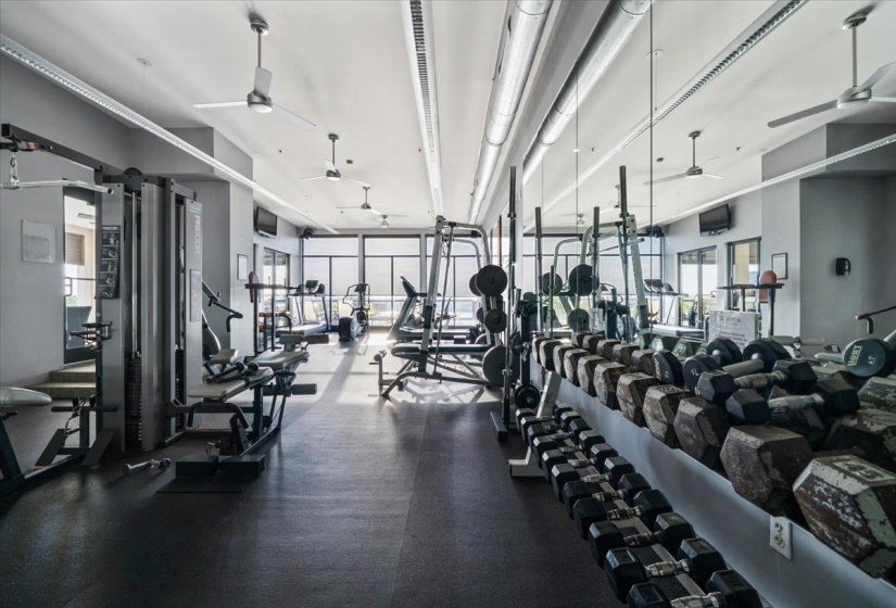 Exercise room with a ceiling fan and floor to ceiling windows