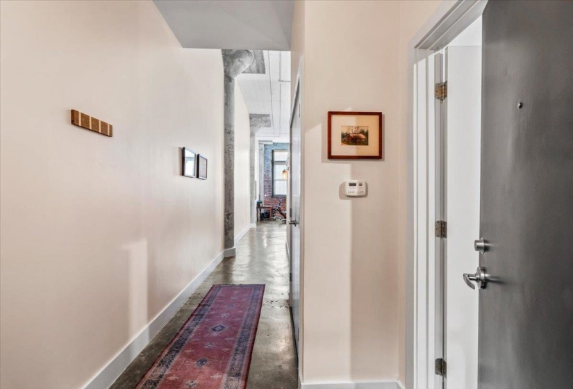Hallway with baseboards and unfinished concrete floors