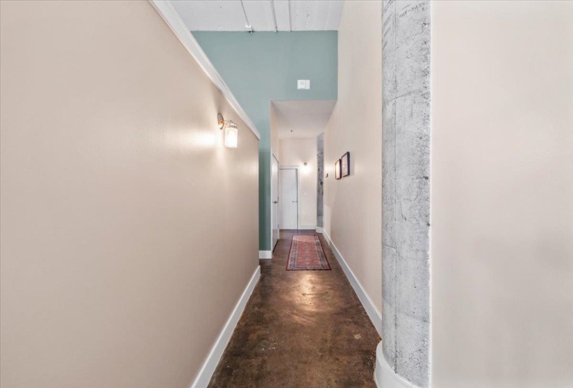 Hallway featuring finished concrete floors and a high ceiling