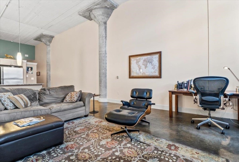 Living area featuring an office area, finished concrete flooring, and ornate columns