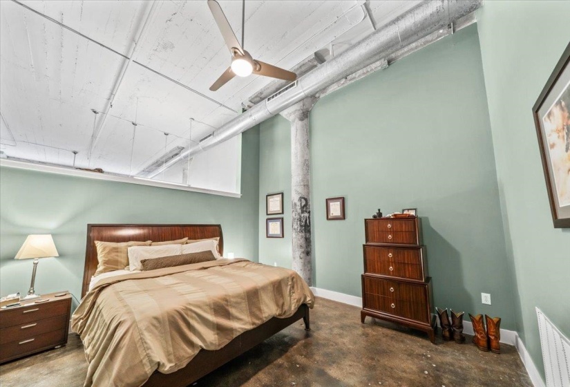Bedroom featuring concrete floors, a ceiling fan, and a high ceiling