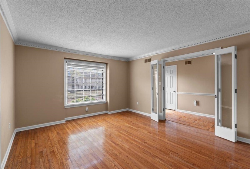 Unfurnished room with light wood finished floors, a textured ceiling, and ornamental molding