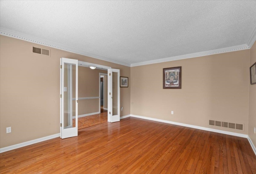 Unfurnished room with crown molding, light wood finished floors, a textured ceiling, and french doors